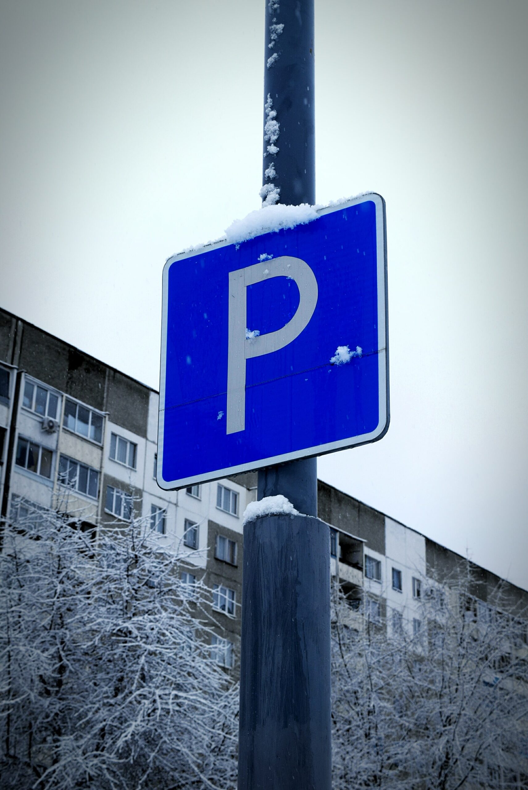 low-angle-view-parking-sign-against-sky-winter-min